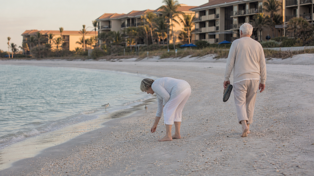 Couple walks barefoot along the Gulf shore near Sand Cay Beach Resort on Longboat Key, picking up shells.